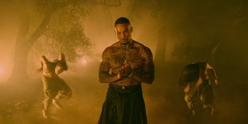 Movie still from “Savage x Fenty Show Vol. 4” (2022), directed by Alex Rudzinski – A man with a tattoo on his chest is holding his hands together; Medium shot, Low angle
