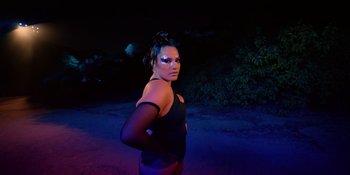 Movie still from “Savage x Fenty Show Vol. 4” (2022), directed by Alex Rudzinski – A woman in a black top standing in the dark; Medium shot, Low angle