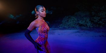 Movie still from “Savage x Fenty Show Vol. 4” (2022), directed by Alex Rudzinski – A woman in a leopard print outfit standing on a beach at night; Medium shot, Over the shoulder angle