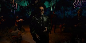 Movie still from “Savage x Fenty Show Vol. 4” (2022), directed by Alex Rudzinski – A man in a leather jacket standing in front of a forest; Wide shot, Low angle