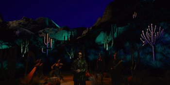 Movie still from “Savage x Fenty Show Vol. 4” (2022), directed by Alex Rudzinski – A group of people standing in front of a desert landscape at night; Extreme Wide shot, Low angle