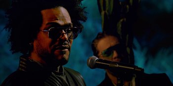 Movie still from “Savage x Fenty Show Vol. 4” (2022), directed by Alex Rudzinski – A man with a microphone and a man with sunglasses; Close Up shot, Low angle