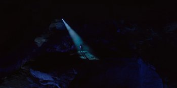 Movie still from “Savage x Fenty Show Vol. 4” (2022), directed by Alex Rudzinski – A man standing in the dark under a beam of light; Extreme Wide shot, High angle