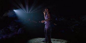 Movie still from “Savage x Fenty Show Vol. 4” (2022), directed by Alex Rudzinski – A man standing on a stage singing into a microphone; Wide shot, Low angle