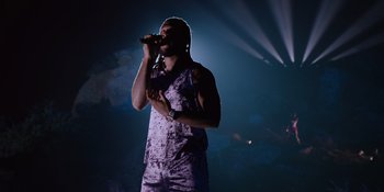 Movie still from “Savage x Fenty Show Vol. 4” (2022), directed by Alex Rudzinski – A man is singing into a microphone on a stage; Medium shot, Low angle