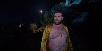 Movie still from “Savage x Fenty Show Vol. 4” (2022), directed by Alex Rudzinski – A man in a yellow robe standing in front of a tree; Medium shot, Low angle