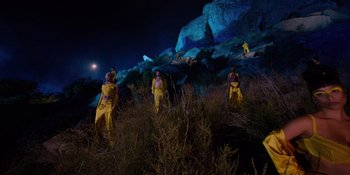 Movie still from “Savage x Fenty Show Vol. 4” (2022), directed by Alex Rudzinski – A group of people standing on top of a grass covered hill; Extreme Wide shot, Low angle