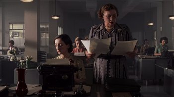 Movie still from “Saving Private Ryan” (1998), directed by Steven Spielberg – Two women are standing at a table with papers; Medium shot, Low angle