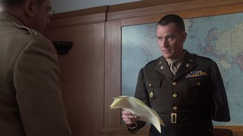 Movie still from “Saving Private Ryan” (1998), directed by Steven Spielberg – A man in a military uniform looking at a piece of paper in front of a mirror; Medium shot, Over the shoulder angle