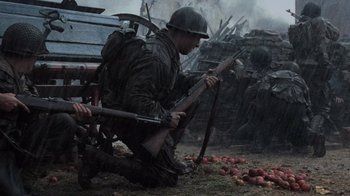 Movie still from “Saving Private Ryan” (1998), directed by Steven Spielberg – A man kneeling on the ground holding a rifle; Wide shot, Low angle