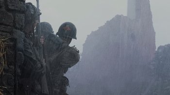 Movie still from “Saving Private Ryan” (1998), directed by Steven Spielberg – Two men in military uniforms standing in the pouring rain; Medium shot, Low angle