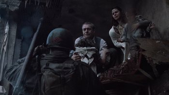 Movie still from “Saving Private Ryan” (1998), directed by Steven Spielberg – A group of people sitting on the ground in a room; Medium shot, Low angle