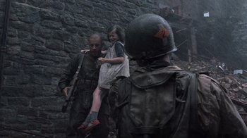 Movie still from “Saving Private Ryan” (1998), directed by Steven Spielberg – A man holding a little girl while standing next to a soldier; Medium shot, Over the shoulder angle