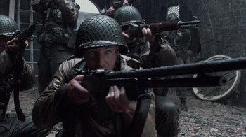 Movie still from “Saving Private Ryan” (1998), directed by Steven Spielberg – A group of men in military fatigues and helmets are holding guns; Medium shot, High angle