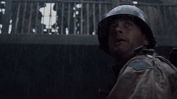 Movie still from “Saving Private Ryan” (1998), directed by Steven Spielberg – A man wearing a helmet in the pouring rain; Close Up shot, Low angle