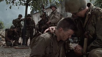 Movie still from “Saving Private Ryan” (1998), directed by Steven Spielberg – A group of men standing next to each other on a dirt ground; Medium shot, Over the shoulder angle