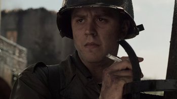 Movie still from “Saving Private Ryan” (1998), directed by Steven Spielberg – A man wearing a helmet and holding a pipe; Close Up shot, Low angle