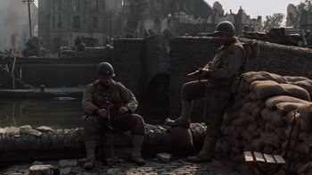 Movie still from “Saving Private Ryan” (1998), directed by Steven Spielberg – Two men dressed in military uniforms sitting next to each other; Wide shot, High angle