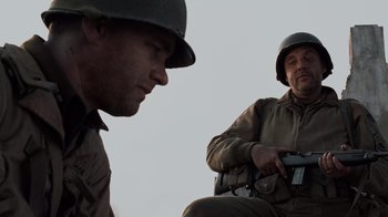 Movie still from “Saving Private Ryan” (1998), directed by Steven Spielberg – Two men dressed in military uniforms are looking at each other; Medium shot, Low angle