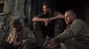 Movie still from “Saving Private Ryan” (1998), directed by Steven Spielberg – A group of men sitting next to each other on the ground; Medium shot, Low angle