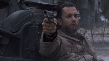 Movie still from “Saving Private Ryan” (1998), directed by Steven Spielberg – A man holding a gun while standing next to a tank; Close Up shot, Low angle