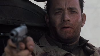 Movie still from “Saving Private Ryan” (1998), directed by Steven Spielberg – A person holding a gun near a car; Close Up shot, Low angle