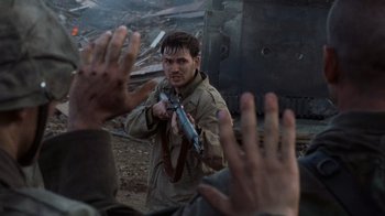 Movie still from “Saving Private Ryan” (1998), directed by Steven Spielberg – A man holding a gun while standing in front of a train; Medium shot, Over the shoulder angle