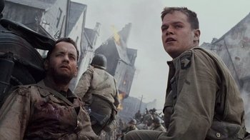 Movie still from “Saving Private Ryan” (1998), directed by Steven Spielberg – Two men in uniforms standing next to each other in a war zone; Medium shot, Low angle