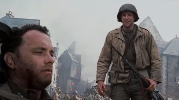 Movie still from “Saving Private Ryan” (1998), directed by Steven Spielberg – A man with a gun standing next to another man; Medium shot, Over the shoulder angle