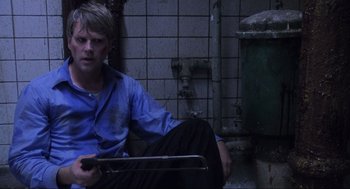 Movie still from “Saw” (2004), directed by James Wan – A man sitting on the ground in a bathroom; Medium shot, Overhead angle