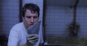 Movie still from “Saw” (2004), directed by James Wan – A man holding a knife in a bathroom; Close Up shot, Low angle