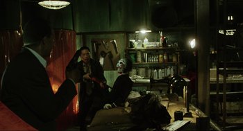 Movie still from “Saw” (2004), directed by James Wan – Two people sitting on a couch in a living room; Medium shot, High angle