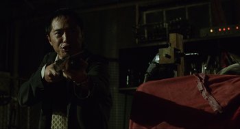Movie still from “Saw” (2004), directed by James Wan – A man holding a gun while standing in a room; Medium shot, Low angle