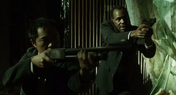 Movie still from “Saw” (2004), directed by James Wan – Two men in black suits are holding a gun; Medium shot, Low angle