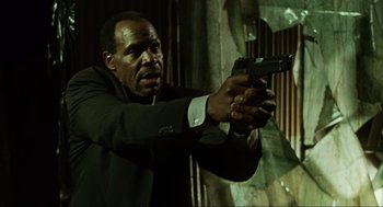 Movie still from “Saw” (2004), directed by James Wan – A man in a suit and tie holding a gun in his hand; Close Up shot, Low angle