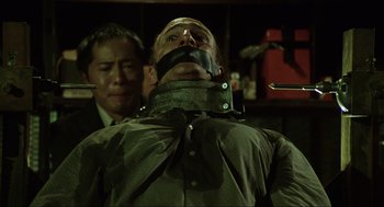 Movie still from “Saw” (2004), directed by James Wan – A man with a head bandaged and a man with a head bandaged and a man with a head bandaged; Medium shot, Low angle