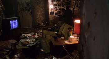Movie still from “Saw” (2004), directed by James Wan – A living room filled with lots of clutter and trash on the floor; Wide shot, High angle