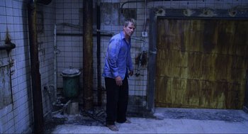 Movie still from “Saw” (2004), directed by James Wan – A man standing in front of an old building; Wide shot, High angle