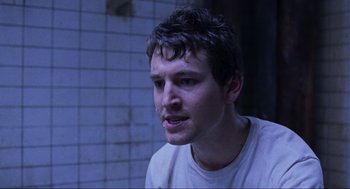 Movie still from “Saw” (2004), directed by James Wan – A young man is sitting in a dark room; Close Up shot, Over the shoulder angle