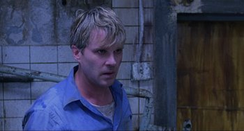 Movie still from “Saw” (2004), directed by James Wan – A man in a blue shirt is looking to his left; Close Up shot, Over the shoulder angle