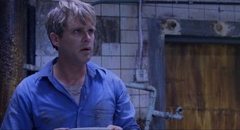 Movie still from “Saw” (2004), directed by James Wan – A man wearing a blue shirt is holding a white plate; Close Up shot, Over the shoulder angle