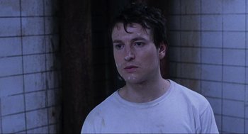 Movie still from “Saw” (2004), directed by James Wan – A young man is looking into the camera; Close Up shot, High angle