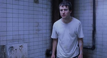 Movie still from “Saw” (2004), directed by James Wan – A man standing in front of a tiled wall; Close Up shot, Low angle