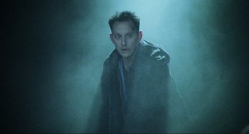 Movie still from “Saw” (2004), directed by James Wan – A young man in a jacket is standing in the fog; Medium shot, Low angle