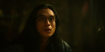 Movie still from “Sayen” (2023), directed by Alexander Witt – A man with long black hair wearing glasses; Close Up shot, Low angle