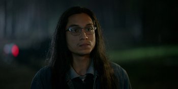 Movie still from “Sayen” (2023), directed by Alexander Witt – A man with long black hair wearing glasses; Close Up shot, Over the shoulder angle