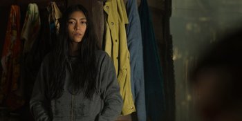 Movie still from “Sayen” (2023), directed by Alexander Witt – A woman standing in front of a row of jackets; Medium shot, Low angle