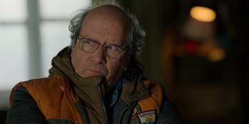 Movie still from “Sayen” (2023), directed by Alexander Witt – An older man wearing glasses and a jacket; Close Up shot, Over the shoulder angle