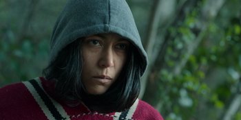 Movie still from “Sayen” (2023), directed by Alexander Witt – A person with a hooded jacket on in the woods; Close Up shot, Low angle