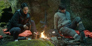 Movie still from “Sayen” (2023), directed by Alexander Witt – A man and a woman sitting next to a fire; Medium shot, Low angle